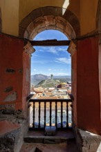 View through an old stone and wooden window of the city and mountains in sunny weather, view of the