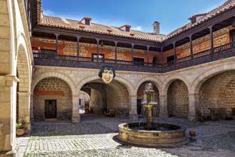 A historic courtyard with a central fountain and arches, surrounded by stone walls and colonial