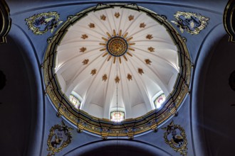 Dome of a church with golden decorations on a blue background and light through windows, inside the