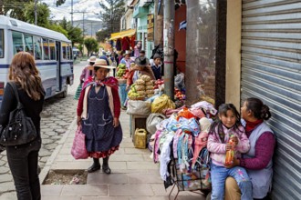 Street with vendors, fruit and clothes, busy with passers-by and a bus, people in the streets of