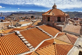 Red roof tiles of a city with colonial architecture, surrounded by mountains under a blue sky, The