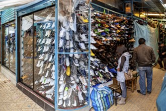 Shoe shop with shelves full of colourful shoes and people shopping, people in the streets of Potosi