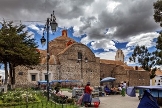 Small church with a round dome next to a busy market square under a partly cloudy blue sky, The old