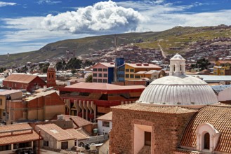 View over a city with tiled roofs and surrounding mountains under a blue sky, view over the city of