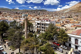 Sweeping view over rooftops of a city with surrounding mountains and blue sky, view over the city