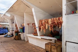 White market stall with meat hung out to dry, sunny atmosphere, rustic surroundings, The meat