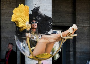 An erotic model sits in an oversized champagne glass at the Grand Opening of the Venus Erotic Fair