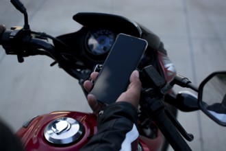 Close up of a motorcyclist holding a phone. Biker using his phone on a motorcycle
