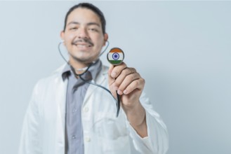 Smiling doctor showing stethoscope with India flag. India national healthcare