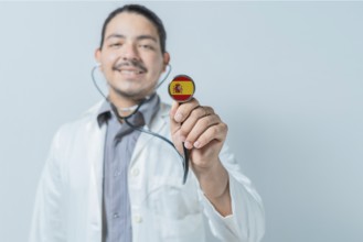 Smiling doctor showing stethoscope with Spain flag. Spain national healthcare