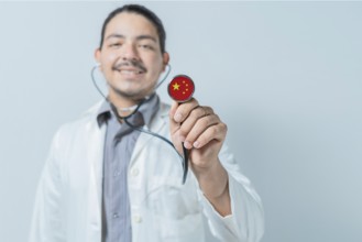 Smiling doctor showing stethoscope with China flag. China national healthcare