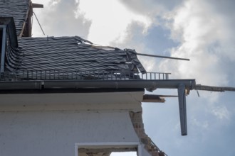 House roof with broken slate tiles and exposed framework showing destruction