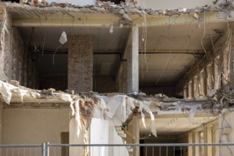 Partially demolished building showing exposed interior structure, rubble, and debris