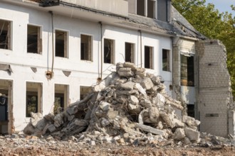 Concrete and brick rubble piling up in front of a partially demolished building