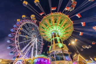 Folk festival time in Stuttgart. Ferris wheel and chain carousel in the evening. The 178th