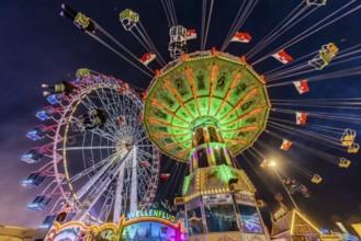 Folk festival time in Stuttgart. Ferris wheel and chain carousel in the evening. The 178th
