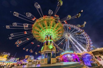 Folk festival time in Stuttgart. Ferris wheel and chain carousel in the evening. The 178th