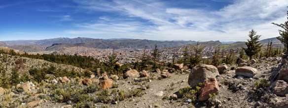 View of a city embedded in a mountainous landscape under a clear blue sky, view over the city of