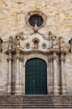 Historic stone façade with large green door and decorative columns, imposing and elegant
