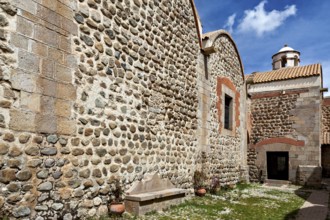 Stone walls and a church entrance under a sunny sky, surrounded by plants, The historical museum of