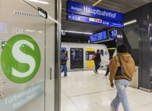 S-Bahn arriving underground at the main station stop. Platform with travellers and logo. Stuttgart,