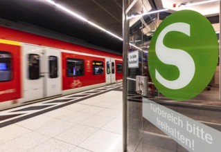 S-Bahn arriving underground at the main station stop. Platform with travellers and logo. Stuttgart,