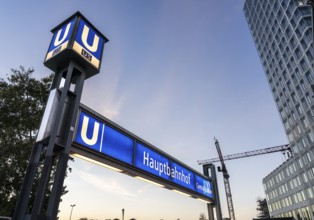 The picture shows a modern high-rise building in Berlin and a striking underground station sign