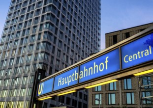 The picture shows a modern high-rise building in Berlin and a striking underground station sign