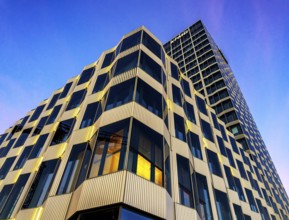The picture shows a modern office and commercial building at the central station, warm evening