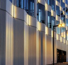 The picture shows a modern office and commercial building at the central station, warm evening