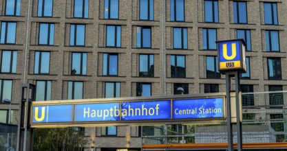 The picture shows a modern high-rise building in Berlin and a striking underground station sign