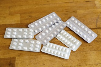 White medical tablets in foil blisters on wooden table top background, UK