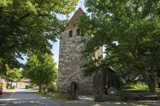 Historic stone church tower surrounded by green trees in the village, Buchholz church, Petershagen,