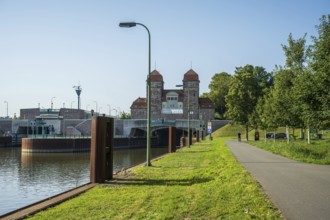 Canal with adjoining lock system and cycle path lined with trees under a blue sky, Minden waterway
