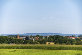 A rural view of a village surrounded by fields and trees under a blue sky, Bielefeld, Westphalia,