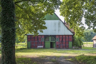 A rustic half-timbered barn with open Tor tor, surrounded by trees and nature, Gütersloh,