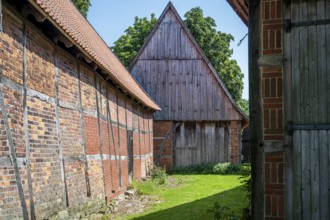Half-timbered buildings in a green courtyard on a sunny day, Weser cycle path, Schlüsselburg barn
