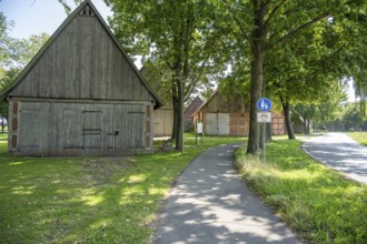 Half-timbered houses next to a cycle path surrounded by green meadows and trees, Weser cycle path,