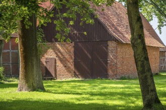 Old brick and timber barn surrounded by trees in rural area, Weser cycle path, Schlüsselburg barn