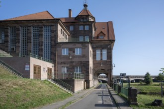 Historic building with red brick roof and large entrance gate under a blue sky, Minden waterway