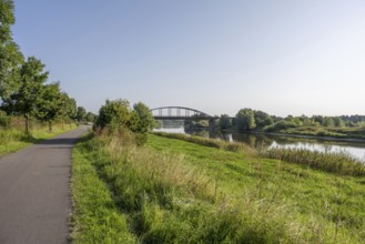 An idyllic river with a bridge surrounded by a green landscape under a clear sky, Weser, Weser