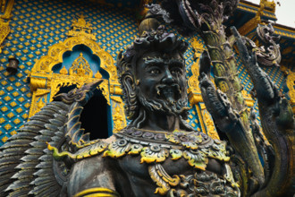 Close-up of a detailed statue with ornate gold and blue highlight in Wat Rong Suea Ten or Blue