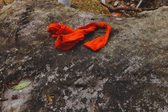 Bright orange cloth resting on a textured rock surface in a natural setting, Thailand