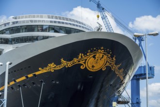 A detailed decorated bow of a cruise ship under a cloudy sky with a crane in the background, cruise