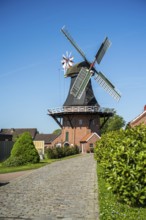 Idyllic windmill near cobbled path and gardens on a sunny day, windmill near Weener