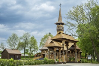 Impressive wooden church with elaborate wood carvings, surrounded by trees under a cloudy sky, The