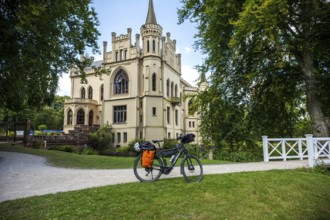 A Gothic castle with a bicycle on a path in idyllic surroundings, Evenburg Castle, Leer, East
