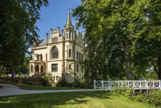 A castle in a peaceful landscape with a bridge in the foreground and a blue sky, Schloss Evenburg,