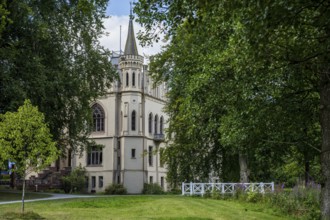 A castle with Gothic elements, surrounded by green landscape and trees, Schloss Evenburg, Leer,