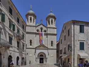 Imposing church with two towers in the historic old town, flanked by sand-coloured buildings under